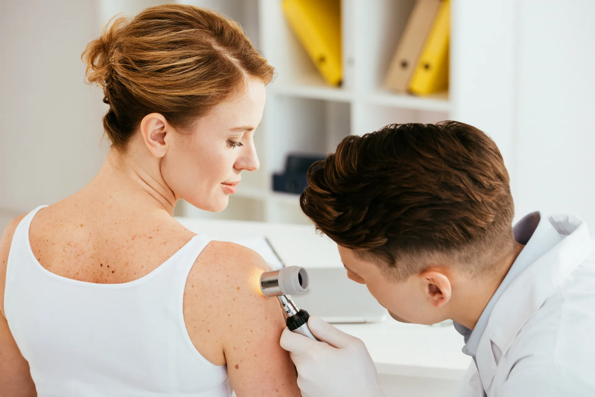 Dermatologie à Granby : médecin examinant au dermatoscope les grains de beauté sur l'épaule d'une patiente